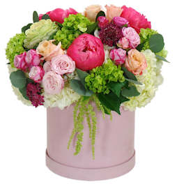 Pink and peach flower arrangement in a round blush box