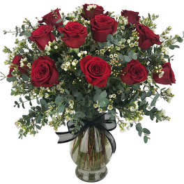 Red roses arranged in a glass vase with white filler flowers