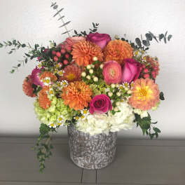 Mixed bouquet of orange, pink, and white flowers in a metal vase