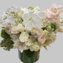 White orchids and pale roses arranged in a green vase