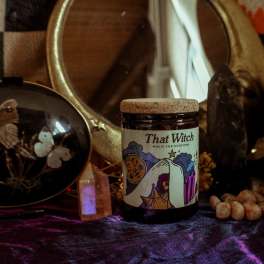 Jar candle labeled "That Witch" on a dark altar-like display