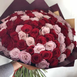 Large bouquet of red and pale pink roses wrapped in dark paper
