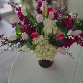 Bouquet of pink and white tulips with white hydrangeas in a dark vase