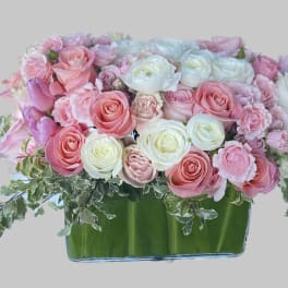 Pink and white roses arranged in a low glass vase
