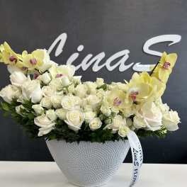 White roses and yellow orchids arranged in a textured white vase
