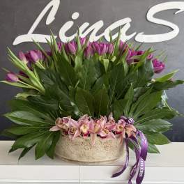 Pink tulips and orchids arranged in a low beige container