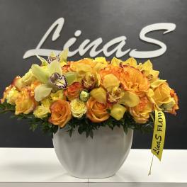 Orange and yellow floral arrangement in a white vase