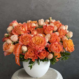 Orange and peach roses arranged in a white vase