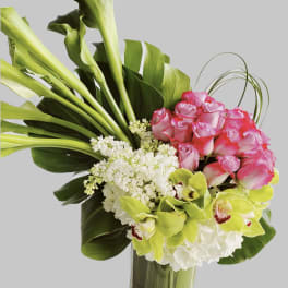 Bouquet of pink roses, green orchids, and white flowers in a tall vase