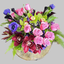 Mixed bouquet of pink roses, orchids, and calla lilies in a gold vase