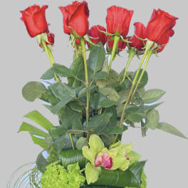 Tall arrangement of red roses and green orchids in a blue vase