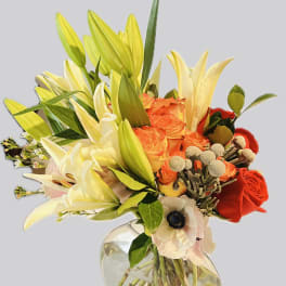 Bouquet of lilies, roses, and anemones in a clear glass vase