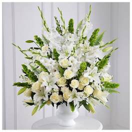Large white and cream floral arrangement with roses and lilies in a white pedestal vase