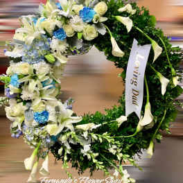 Round sympathy wreath with white lilies, roses, blue flowers, and a Loving Dad ribbon.