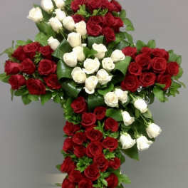 Cross-shaped arrangement of red and white roses on a neutral background