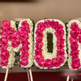 Standing floral letters spelling MOM with pink roses and white flowers on easels.