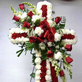 Tall red and white floral cross on an easel with red roses, carnations, and a satin ribbon