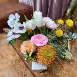 Mixed bouquet with white, pink, and peach flowers in a low vase