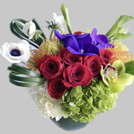 Bouquet of red roses, purple orchids, and white blooms in a vase
