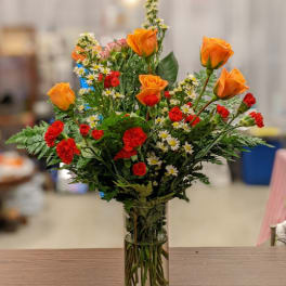 Orange roses and red carnations in a clear glass vase