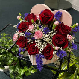Heart-shaped box of red roses with pink carnations and purple filler flowers