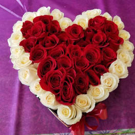 Heart-shaped bouquet of red and white roses with a red ribbon
