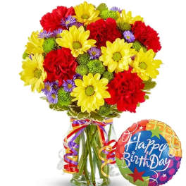 Colorful bouquet of daisies and carnations in a glass vase with a birthday balloon