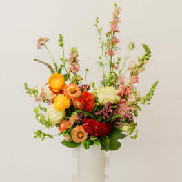 Colorful mixed bouquet in a white vase with tall pink stems