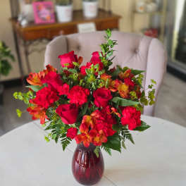 Bouquet of red roses and orange alstroemeria in a burgundy vase