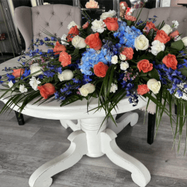 Large floral centerpiece with coral, white, and blue flowers on a white table