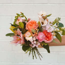 Hand-tied bouquet of pink and coral flowers with mixed blooms