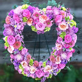 Heart-shaped floral wreath of pink and purple roses on a stand