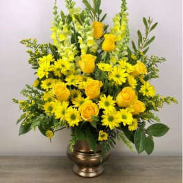 Tall yellow arrangement with roses, daisies, and snapdragons in a bronze urn vase
