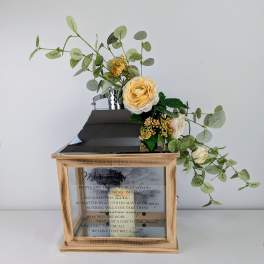 Floral arrangement with cream roses and eucalyptus in a wooden memorial lantern