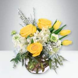Yellow roses and white flowers in a glass vase