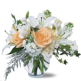 Peach roses and white lilies in a clear glass vase