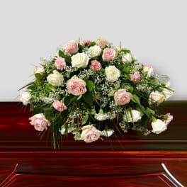 Pink and white roses arranged on a wooden casket