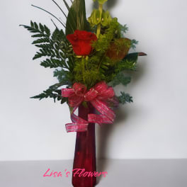 Red rose arrangement in a tall red vase with a pink ribbon
