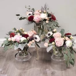 Three pastel floral arrangements in clear glass vases