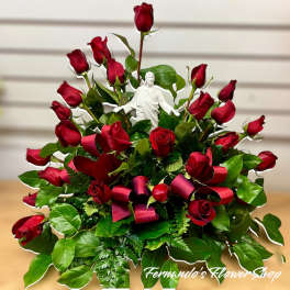 Fan-shaped arrangement of red roses with a white Jesus figurine and red ribbon loops