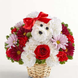 Flower arrangement shaped like a white dog with a red bow in a wicker basket