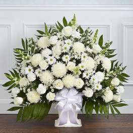 Large white floral arrangement in a white vase with a satin ribbon