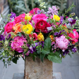Bright mixed bouquet of roses and ranunculus in a rustic vase