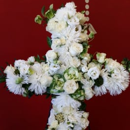 White floral cross on a stand against a red background