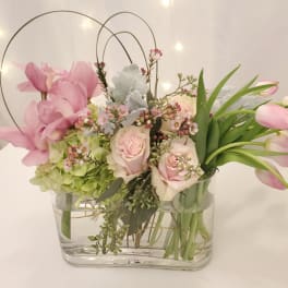 Pink tulips and roses arranged in a clear glass vase