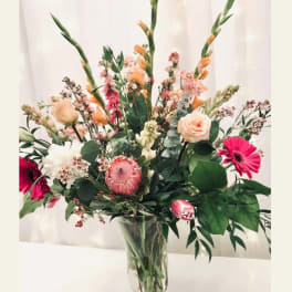 Tall mixed bouquet in a clear glass vase with pink and peach blooms