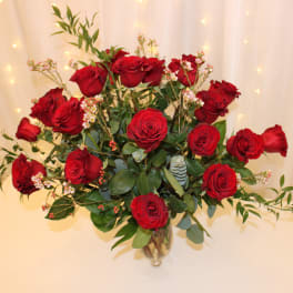 Red roses arranged in a clear glass vase with greenery