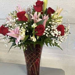 Red roses and pink lilies arranged in a tall vase