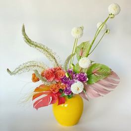 Colorful floral arrangement in a yellow vase with white pom-pom blooms