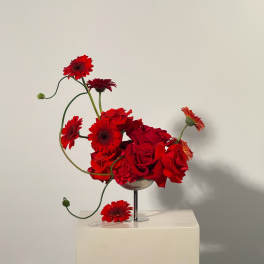 Red roses and gerbera daisies in a glass vase
